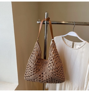 Close-up of bohemian hollow crochet pattern on natural straw hobo bag with leather strap