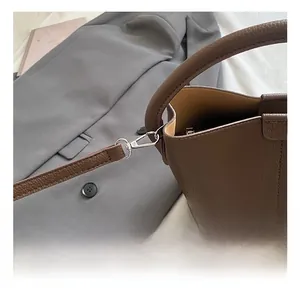 Détail du crochet en métal argenté et cuir grainé sur un sac seau marron chic