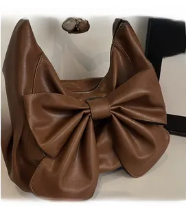 Close-up of brown PU leather shoulder bag featuring large bow and white lace trim