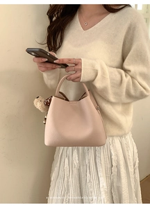 Detailed view of pale pink bucket bag with a cute teddy bear charm and dotted bow decoration