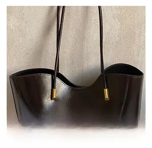 Détail du cabas en cuir marron brillant avec ferrures dorées et fines bandoulières