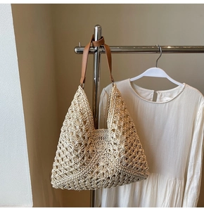 Detail of hollow-out beige woven tote bag with premium brown leather shoulder straps