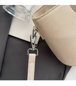 Détail d'un sac seau beige avec des crochets argentés polis et une bandoulière amovible