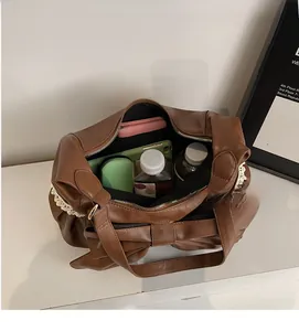 Spacious interior of brown faux leather tote bag with bow detail holding daily essentials