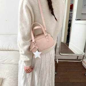 Detail of pink PU leather Boston bag with star pendant shown on a model's back