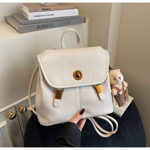 Close-up of cream white pleated PU leather backpack with gold clasp and plush bear charm