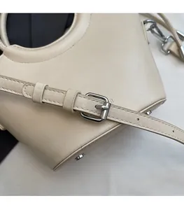 Détail du sac seau en cuir crème avec bandoulière réglable et ferrures en argent poli