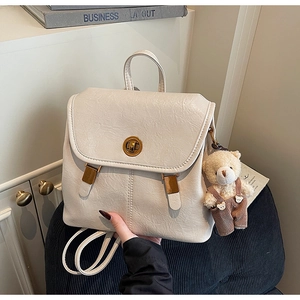 Detail of off-white faux leather backpack with gold twist lock and cute bear charm