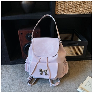 Détail d'un sac à dos rose pâle avec boucle métallique en nœud et fermeture à cordon