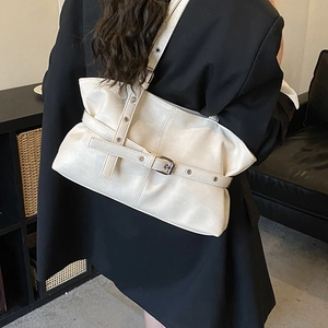 Détail du sac hobo blanc plissé avec sangles à œillets porté sur l'épaule par un mannequin