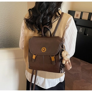 Detail of vintage dark brown faux leather backpack featuring gold twist lock and bear charm