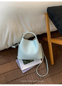 Detail of light blue bucket bag with pebble leather texture and silver metal hardware