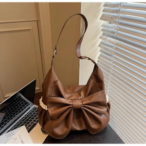 Detail of caramel brown matte leather tote with large bow and white lace trim