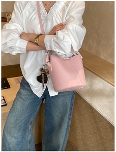Détail du sac seau en cuir rose avec breloque cœur léopard et bandoulière réglable