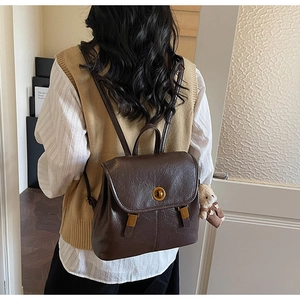Detail view of vintage dark brown leather backpack with gold clasp and bear charm