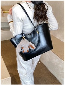 Détail d'un grand cabas noir en cuir avec un charmant lapin en peluche sur le côté