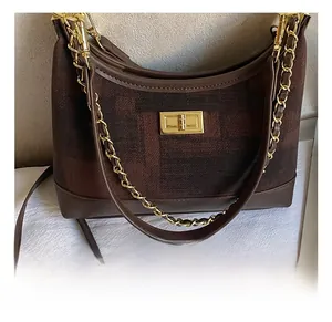 Detail of retro jacquard fabric stitching and golden twist lock on a brown shoulder bag