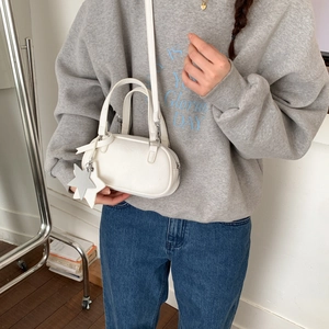 Macro shot of a white mini Boston bag with star charm and detachable shoulder strap
