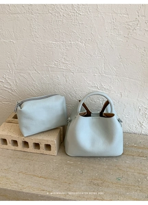 Macro view of light blue lychee-grain leather bucket bag and matching internal pouch