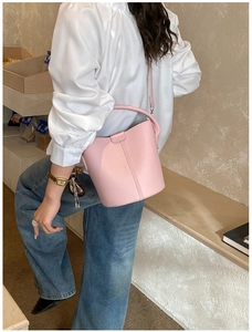 Sac seau rose avec texture cuir grainé et boucle en métal porté par un mannequin