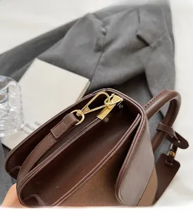 Close-up of golden metal buckle and contrast texture on brown leather handbag