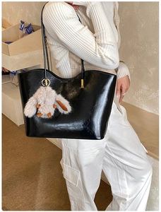 Gros plan d'un sac cabas noir brillant avec un charmant lapin en peluche gris