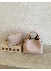 Chic beige bucket bag set with matching zippered pouch on minimalist stone pedestal