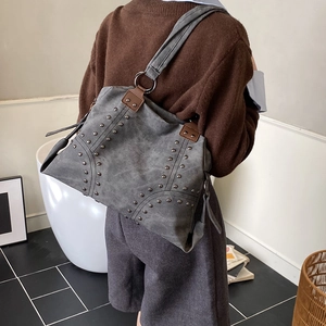 Détail d'un sac cabas en daim gris avec rivets métalliques et design style biker