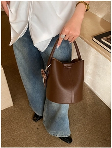 Gros plan d'un sac seau en cuir grainé marron foncé avec pendentif en peluche léopard