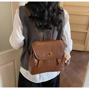 Detail of vintage brown PU leather backpack with gold metal lock and plush bear pendant