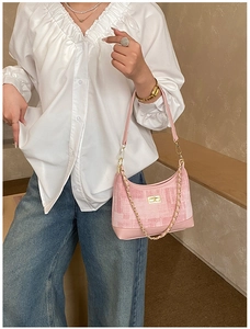 Detail of pink textured hobo bag with gold chain and square buckle on model shoulder