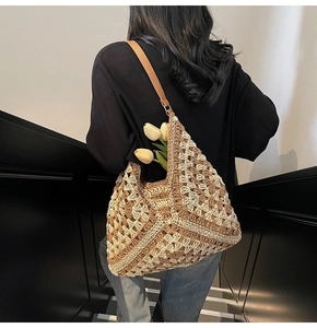 Detail of hand-woven tote bag with geometric patterns and a brown leather strap