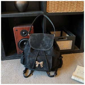 Détail du sac à dos en daim noir avec cordon de serrage et boucle de nœud doré