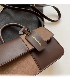 Detail view of contrast color splicing bag with smooth brown leather and matte texture
