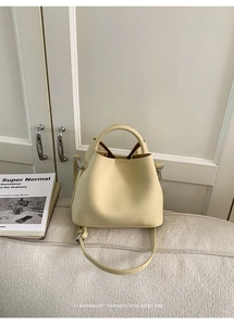 Detail view of cream bucket bag showing fine lychee grain texture and silver hardware