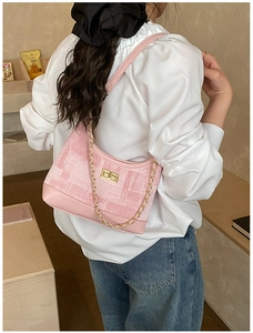 Detail of pink tweed shoulder bag with golden chain and metallic twist lock on model