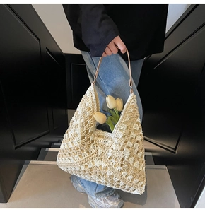Detail of hand-woven hollow pattern on off-white crochet tote with brown leather handle