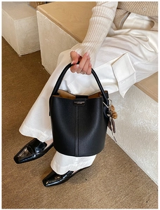 Détail du sac seau en cuir grainé noir avec charme léopard et poignée élégante