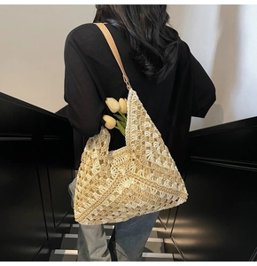 Detail of hand-woven straw tote with hollow pattern and premium brown leather strap