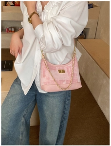 Detail of pink plaid hobo bag with golden chain and clasp worn with casual white shirt