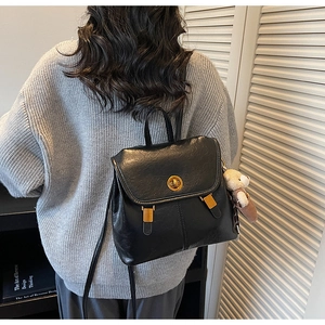 Lifestyle view of retro black PU leather backpack with gold buckles and bear charm