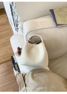 Close-up of cream white bucket bag with pebble leather texture and polka dot bow detail