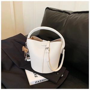 Détail du sac seau blanc motif litchi avec poignée ronde et breloque léopard