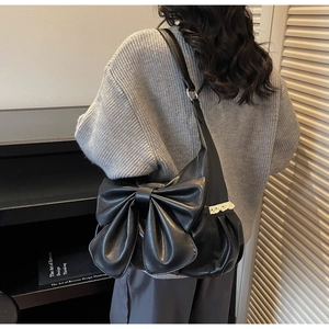Close-up of black PU leather shoulder bag featuring a large bow and white lace trim detail