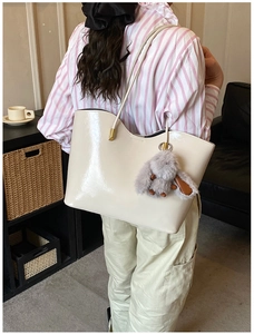 Détail du grand sac cabas en cuir verni blanc cassé avec bord ondulé et breloque lapin