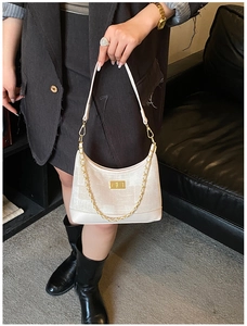 Detail of beige hobo bag featuring gold chain strap and metallic twist lock closure