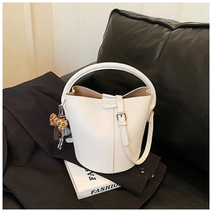 Détail du sac seau en cuir blanc texturé avec un accessoire nœud à motif léopard