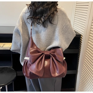 Close-up of dark red hobo bag with large bow and delicate white lace trim detail