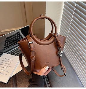 Détail du sac seau en cuir marron avec breloque cœur et inscription NO FILTER gravée
