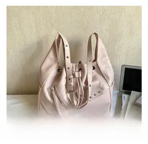 Close-up of pink faux leather tote with metal studs and zippers in a lifestyle setting